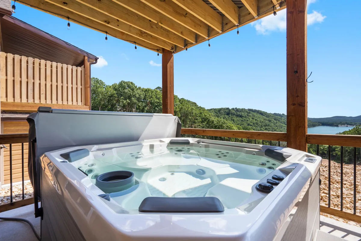 An inviting outdoor hot tub nestled in nature, with a clear view of the water beyond. The scene captures the tranquility of the setting, including lush greenery and a spacious area for relaxing or entertaining guests.