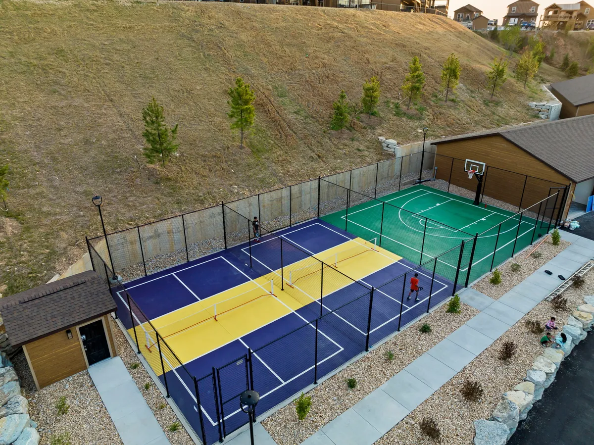 An energetic outdoor sports area featuring tennis courts and a basketball court, surrounded by greenery. The courts are designed for friendly competition, group activities, and engaging with the outdoors, ideal for guests looking for active entertainment.